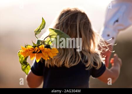 Junge Mädchen gehen Hand in Hand mit ihrem Vater und die Sonnenblume. Stockfoto