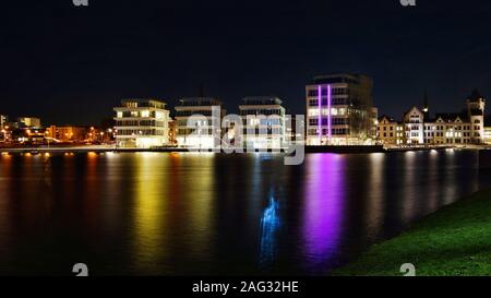 Breite Aufnahme von Wasser in der Nähe von Gebäuden mit beleuchteten Lichtern und Ein dunkler Himmel im Hintergrund bei Nacht Stockfoto