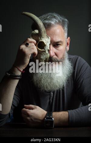 Dunkle Portrait eines bärtigen Mann mittleren Alters mit einem Tier Schädel, selektiven Fokus Stockfoto