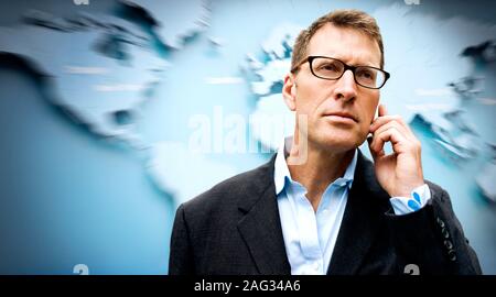 Porträt einer durchdachten Geschäftsmann stand vor einer Weltkarte. Stockfoto