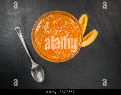 Pfirsich Marmelade auf einem Vintage schiefer Tafel als detaillierte Nahaufnahme; selektive Fokus Stockfoto