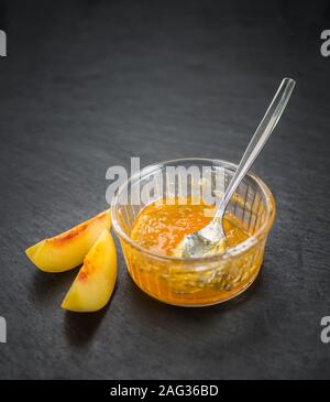 Pfirsich Marmelade auf einem Vintage schiefer Tafel als detaillierte Nahaufnahme; selektive Fokus Stockfoto