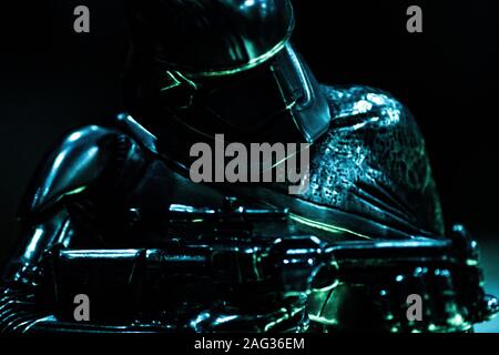 Dunkle Aufnahme eines Roboters mit Metallkleidung und Halteplatte Eine Waffe mit schwarzem Hintergrund Stockfoto