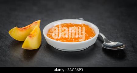 Pfirsich Marmelade auf einem Vintage schiefer Tafel als detaillierte Nahaufnahme; selektive Fokus Stockfoto