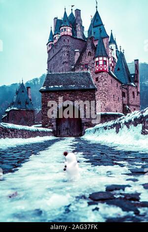 Vertikale Aufnahme des Schlosses Eltz in Wierschem Deutschland in Winter mit einem kleinen Schneemann in der Front Stockfoto