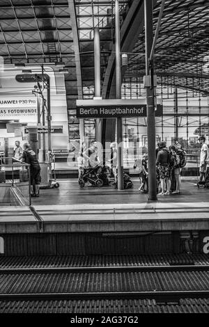 Vertikale Graustufenaufnahme des Berliner Hauptbahnhofs und der Menschen Auf der Plattform Stockfoto