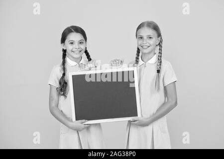 Fröhliche Freunde in retro Uniform. vintage Kid Mode. zurück zu Schule. kleine Mädchen Tafel halten. Kinder Bildung. Mädchen präsentiert Informationen. alte Schule. Kopieren Sie Platz an Bord. Werbung. Stockfoto