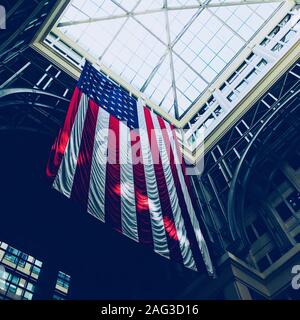 Low-Angle-Aufnahme der amerikanischen Flagge, die in einem hängt Gebäude unter Glasdecke tagsüber Stockfoto