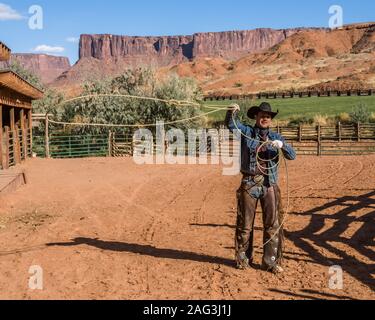 Ein cowboy Wrangler twirling seiner Lariat auf der Red Cliffs Ranch in der Nähe von Moab, Utah. Er trägt leder chaps seine Beine von dornige Bürste zu schützen, während RID Stockfoto