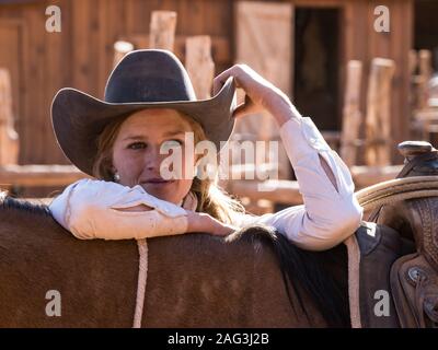 Eine junge attraktive Arbeitsbedingungen cowgirl Wrangler stellt mit ihrem Pferd auf einer Ranch in der Nähe von Moab, Utah. Stockfoto