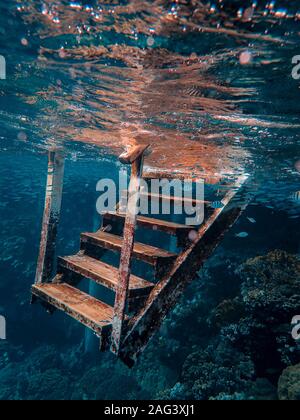 Schöne vertikale Aufnahme einer verrosteten Metalltreppe unter dem Meer Stockfoto