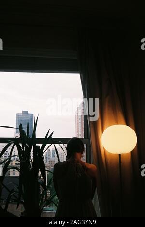 Vertikale Aufnahme einer einsamen Frau mit dem Kopf nach unten Neben einem Balkon neben einer Lampe Stockfoto