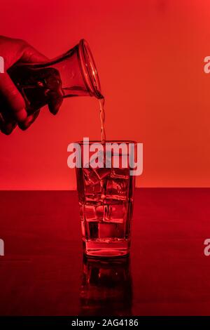 Vertikale Aufnahme von zwei Gläsern Eiswasser in rot Leicht Stockfoto