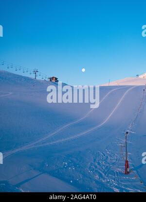 Vertikale Aufnahme einer Skipiste in verschneiten Bergen in der Nähe Eine Seilbahn unter dem wunderschönen blauen Himmel Stockfoto