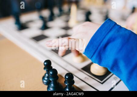 Nahaufnahme eines menschlichen Armes in einer blauen Bluse Schachfiguren auf einem Schachtisch bewegen Stockfoto