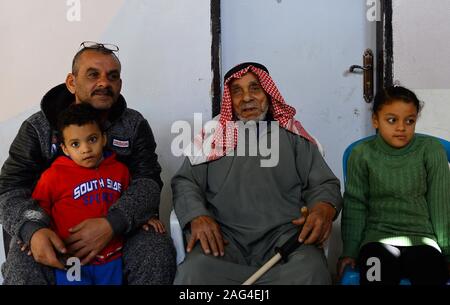 (191218) - GAZA, Dez. 18, 2019 (Xinhua) - suleiman Abu-Namous (C) sitzt mit seiner Familie im Flüchtlingslager Jabalia im nördlichen Gazastreifen, Dez. 17, 2019. Suleiman Abu-Namous aus Gaza vor kurzem stieß einen Seufzer der Erleichterung nach Anhörung, dass das Mandat der Vereinten Nationen für Palästinaflüchtlinge im Nahen Osten (UNRWA) für weitere drei Jahre verlängert werden. Die UNRWA hat ein rettungsseil und ein Anbieter von grundlegenden Dienstleistungen für rund fünf Millionen palästinensischen Flüchtlinge in der Region, einschließlich der 110 Jahre alte Mann und seine Familie. Gehen mit 'Feature: palestinia Stockfoto