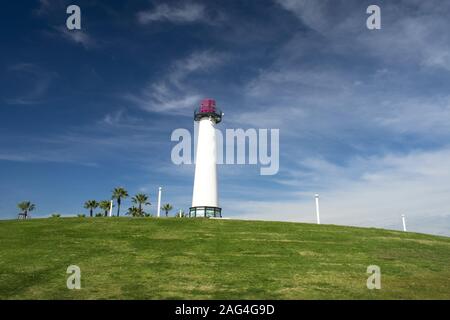 Low-Angle-Aufnahme eines Leuchtturms in einem Grün isoliert Feld unter dem schönen bewölkten Himmel Stockfoto