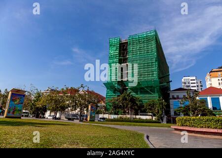 Ein neues Gebäude mit Blick auf den historischen Wat Botum Park ist mit grünen Sicherheit drapiert Verrechnung während im Bau in Phnom Penh, Kambodscha. Stockfoto