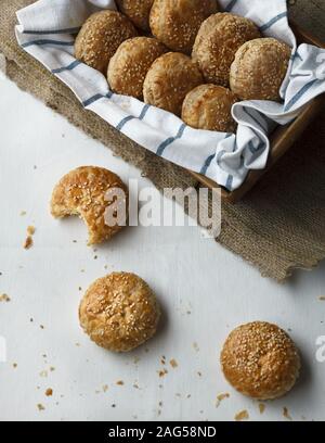 Eine gebissene Krokette in der Nähe eines Korbes voller hausgemachter Kroketten Auf einem weißen Tisch mit Krümel bedeckt Stockfoto