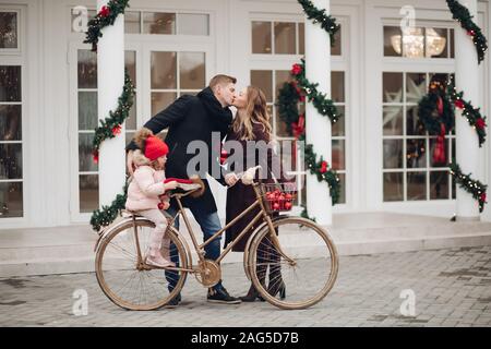 Winter Familie Gefühl der Liebe auf Vintage Fahrrad zu Weihnachten outdoor Dekoration Hintergrund posiert Stockfoto