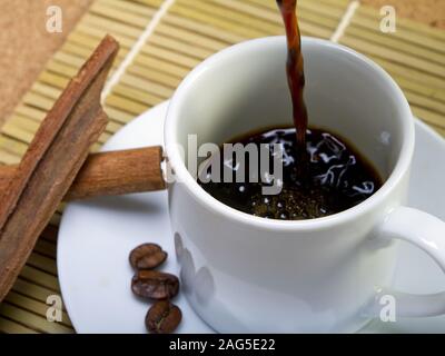 In eine Tasse gegossener Kaffee aus dem hohen Winkel Mit etwas Zimt daneben Stockfoto