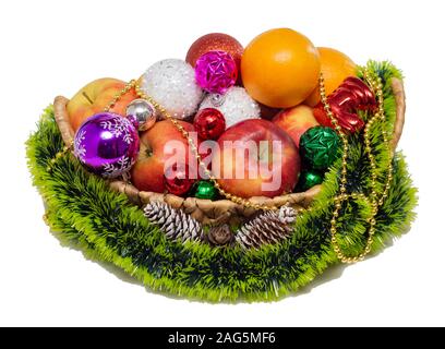 Obst Äpfel und Mandarinen Weihnachtsbaum Spielzeug Bälle Kegel in Weihnachten Korb isoliert weißer Hintergrund close-up Stockfoto