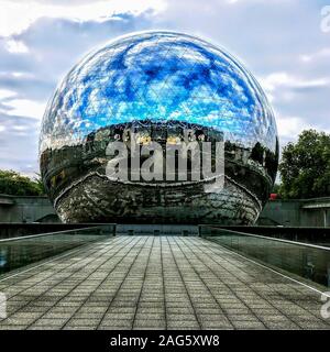 Schöne Aufnahme einer Landschaft, die sich in einem riesigen Spiegel spiegelt Ball unter dem wolkigen Himmel Stockfoto