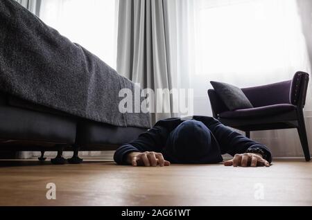 Junge Mann in dunklem hoodie auf einer Etage zu Hause legt, emotionale Krise Konzept Stockfoto