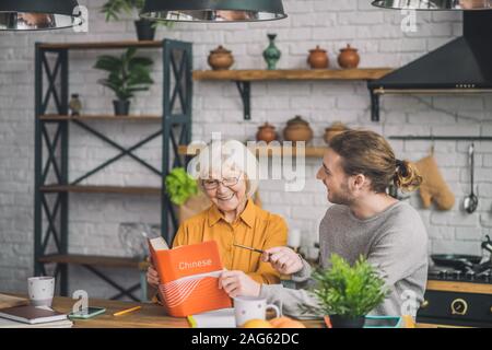 Gespräch. Elegante gut aussehende grauhaarige Frau und ihr Sohn ein Buch diskutieren Stockfoto