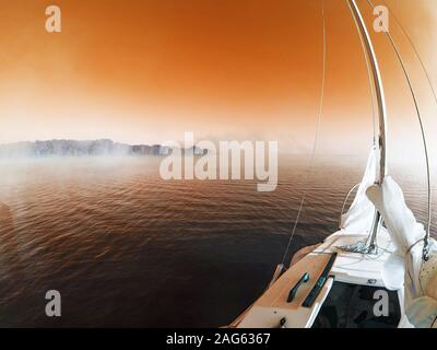 Schöne Aufnahme von Olympus OM-D Boot Segeln am Morgen Mit dem orangefarbenen Himmel im Hintergrund Stockfoto