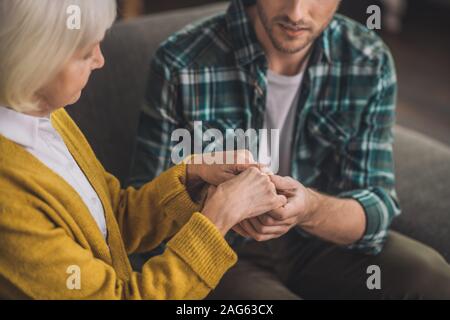 Dankbar Sohn. Jungen gutaussehenden Mann seinen Mammen Hände halten mit Liebe Stockfoto