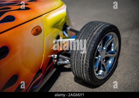 Nahaufnahme eines orangefarbenen Fahrzeugrad mit einem schwarzen Reifen auf Asphalt geparkt Stockfoto