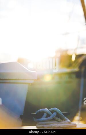 Vertikale Nahaufnahme eines Knotens auf dem Boot mit Die Sonne scheint im verschwommenen Hintergrund Stockfoto