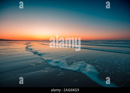 Schöne Aussicht auf die schäumenden Wellen am Strand unter dem Sonnenuntergang in Domburg, Niederlande aufgenommen Stockfoto