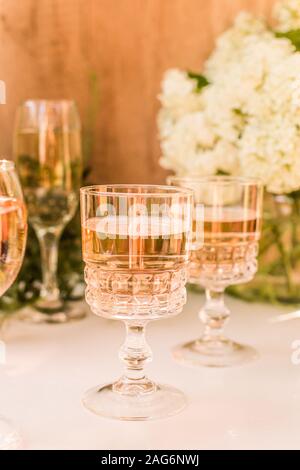 Rose Blush Wein in Gläsern. Flasche Rosewein mit Blumen auf Hintergrund. Prosecco. Stockfoto