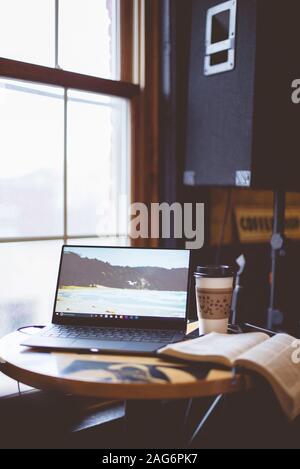 Vertikale Aufnahme des Laptops in der Nähe einer bibel und Kaffee auf Der Tisch mit verschwommenem Hintergrund Stockfoto