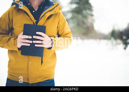 Nahaufnahme eines Mannes mit gelber Jacke und Hält die bibel gegen seine Brust Stockfoto