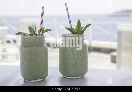 Nahaufnahme von zwei Smoothies in Maurer-Gläser mit Minze Blätter oben auf einem unscharfen Hintergrund Stockfoto