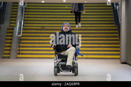 Ludwigsburg, Deutschland. 17 Dez, 2019. Steffen Gödecke steht mit seiner elektrischen Rollstuhl vor einer Treppe in der Station. Credit: Marijan Murat/dpa/Alamy leben Nachrichten Stockfoto