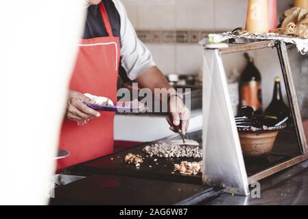 Nahaufnahme des Küchenchefs, der das Essen mit einem zubereitet Unscharfer Hintergrund Stockfoto