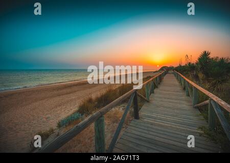 Schöne hölzerne Pier am Strand mit Sonnenuntergang im Hintergrund in Andalusien, Spanien gefangen genommen Stockfoto