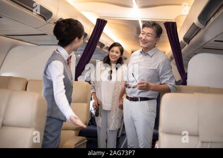 Chinesischer Flugbegleiter und Passagiere im Flugzeug Stockfoto