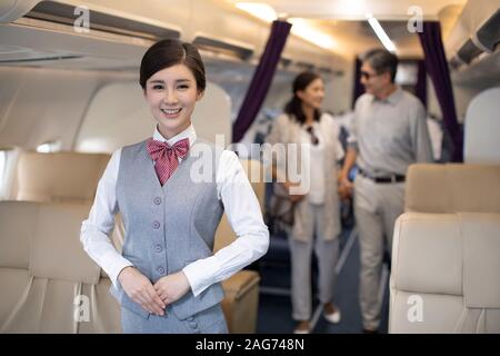 Chinesischer Flugbegleiter und Passagiere im Flugzeug Stockfoto