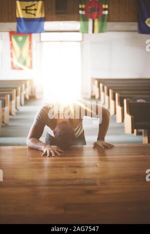 Vertikale Aufnahme eines Männchens mit dem Kopf auf einem Holzfläche in der Kirche beten Stockfoto