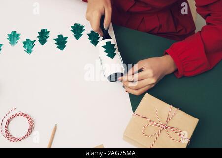 Das Mädchen am Tisch macht Weihnachten Geschenke. Hand Made Stockfoto