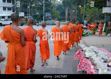 Chiang Mai, Thailand - Dezember 12, 2019: buddhistischer Mönch zu Fuß mit Schüssel Almosen Nahrung von Menschen bei Huaw Kaew Road in Chiang Mai, Thailand zu erhalten Stockfoto