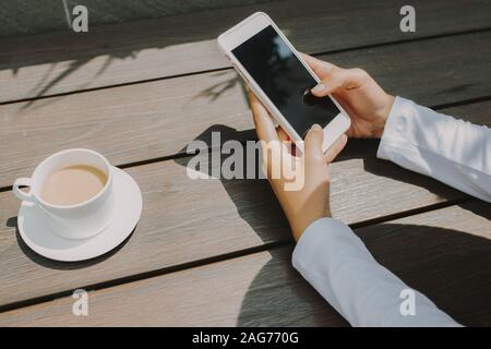 Frau hand Texting für jemanden mit schwarzen Bildschirm Coffee Shop Stockfoto