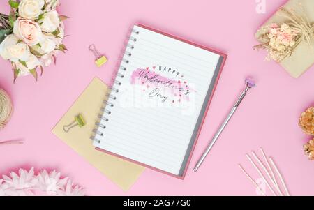 Mockup Notebook auf rosa Hintergrund mit Happy Valentines Day, Rosen, Blumenstrauß, Geschenkbox, praktische Fertigkeit und Stift. Mock up für elegantes Design mit Platz für Stockfoto