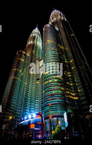 Vertikale Low-Angle-Aufnahme der berühmten Petronas Twin Towers in Kuala Lumpur, Malaysia bei Nacht Stockfoto