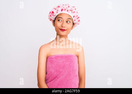 Junge chinesische Frau mit Handtuch und die Badewanne Dusche über isoliert weißer Hintergrund lächelnd auf die Seite und starrte weg denken. Stockfoto